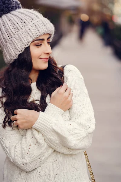 Leuke brunette in een witte trui in een stad — Stockfoto
