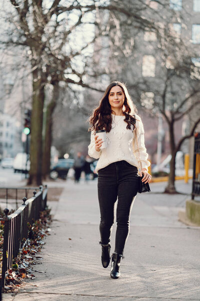 Симпатичная брюнетка в белом свитере в городе