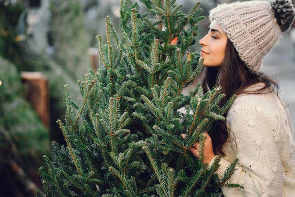 Χαριτωμένη μελαχρινή σε ένα λευκό πουλόβερ με χριστουγεννιάτικο δέντρο — Φωτογραφία Αρχείου