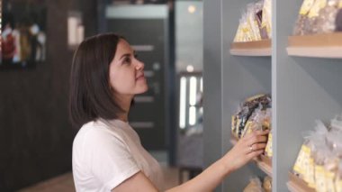 Mağazadaki kurumuş meyve raflarına bakan çekici kadın müşteri.