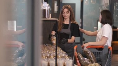 Kadın müşteri marketten bir kadın satıcıyla kurutulmuş meyve seçiyor.
