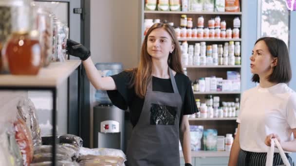 Női ügyfél választja szárított gyümölcsök a boltban egy női eladó — Stock videók