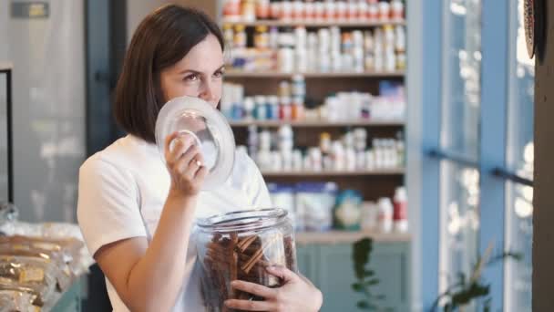 Femme avec un pot en verre de bâtonnets de cannelle au magasin — Video