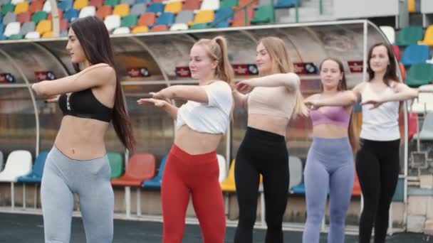 Fem ganska sportiga tjejer gör uppvärmning upp innan träningen på stadion — Stockvideo