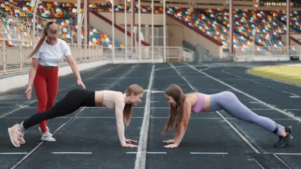 Sportkvinnor och tränare gör knäböj med motstånd fitness gummiband på stadion — Stockvideo