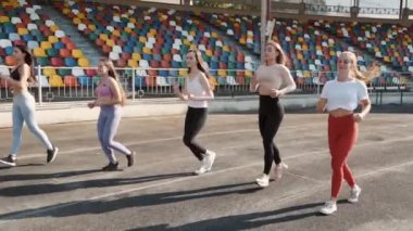 Gün batımında stadyumda koşan iki güzel kadın.