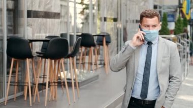 Koruyucu maskeli serbest iş adamı telefonla konuşuyor.