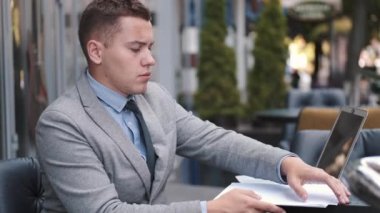 Dışarıdaki kafede gazetelerle çalışan bir işadamı.
