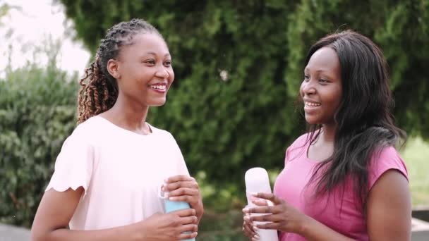 Duas meninas afro-americanas bebendo água depois de treinar ao ar livre — Vídeo de Stock