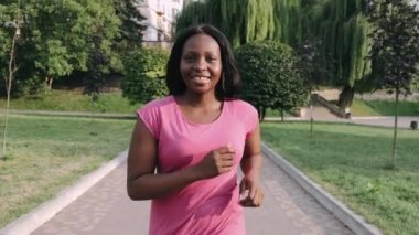 Genç aktif Afrikalı Amerikalı kadın sağlıklı kalmak için parkta koşuyor.