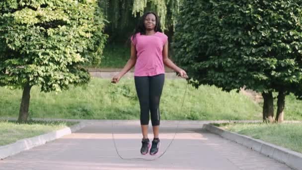 African american woman makes a jump rope routine in a city park — Stock Video