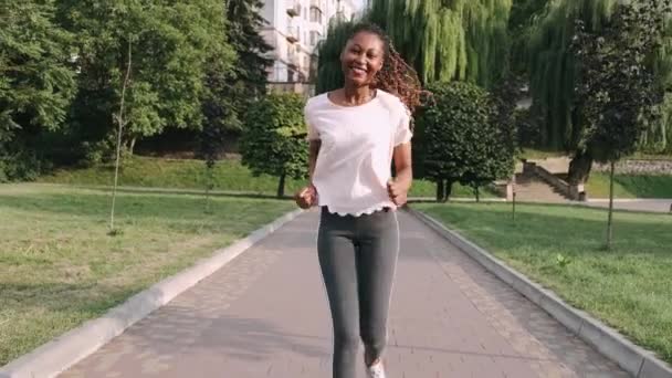 Jonge actieve Afro-Amerikaanse vrouw joggen in park om gezond te houden — Stockvideo