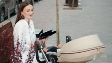 Annem bebek arabasında bir bebekle bankta oturuyor ve gazete okuyor.