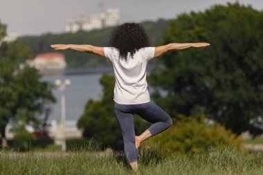 Yaşlı kadın yaz parkında yoga yapıyor.