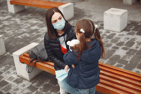 Mujer con una máscara desechable está enseñando a su hijo a usar un respirador — Foto de Stock