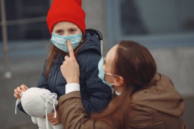 Kızıyla birlikte solunum cihazına bağlı Avrupalı bir anne binanın yanında duruyor. Ebeveyn kendini virüsten korumak için çocuğuna koruyucu maske takmayı öğretiyor.