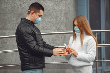 Koruyucu maskeler takan gençler el dezenfektanı sıkıyorlar.