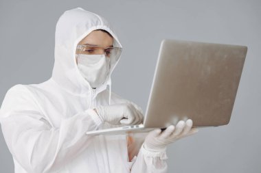 Koruyucu takım elbiseli ve gözlüklü adam stüdyoda.