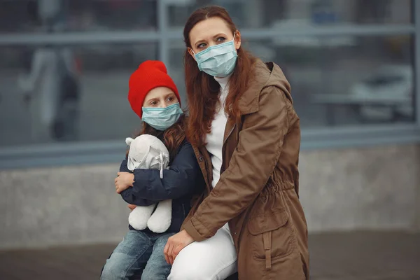 彼女の娘と一緒に呼吸器でヨーロッパの母親が建物の近くに立っています。親は彼女の子供にウイルスから身を守るために保護マスクを着用する方法を教えています — ストック写真