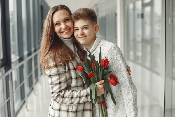 Syn dává matce hromadu červených tulipánů v moderní síni — Stock fotografie