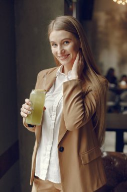 Bir kafede durup kokteyl içen zarif bir kadın.