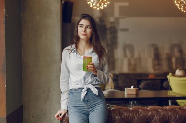 Mavi bluzlu zarif kadın bir kafede vakit geçiriyor.