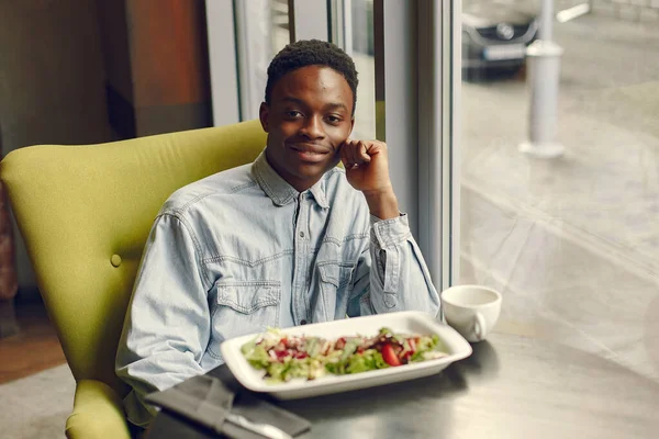 Uomo nero seduto in un caffè e mangiare un'insalata di verdure — Foto Stock