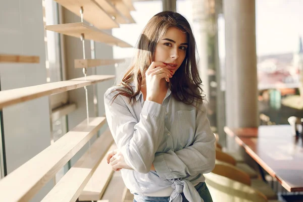 Chica sonriente en una camisa azul de pie cerca de la ventana y posando — Foto de Stock