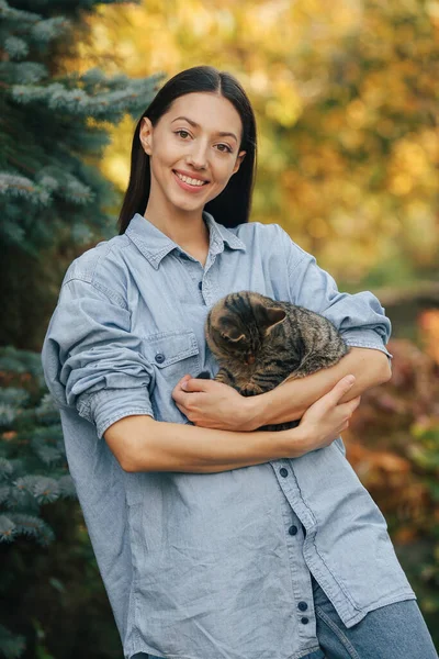 Dívka v modré košili stojící na stromech pozadí — Stock fotografie