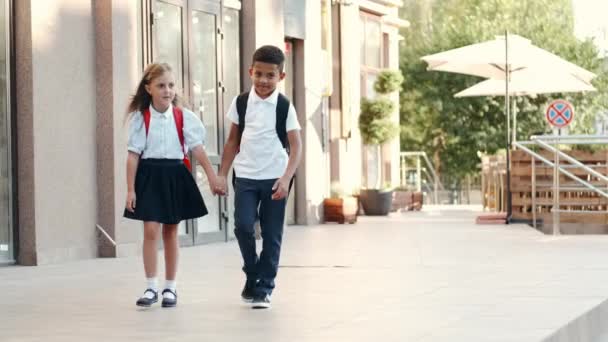Děti s batohy se vrací ze školy a usmívají se. — Stock video