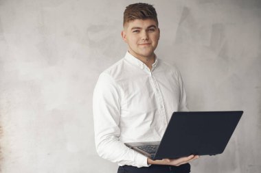 Ofiste çalışan şık bir iş adamı ve dizüstü bilgisayarı kullanıyor.