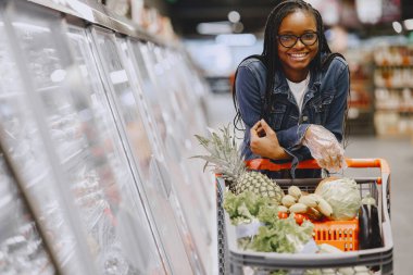 Kadın süpermarkette sebze alışverişi yapıyor.