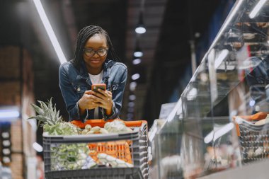 Kadın süpermarkette sebze alışverişi yapıyor.