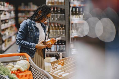 Kadın süpermarkette sebze alışverişi yapıyor.