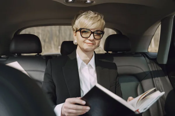 Empresaria sentada dentro de un coche y usando un cuaderno — Foto de Stock