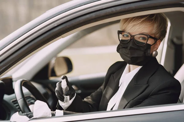 Mujer de negocios con una máscara negra sentada dentro de un coche — Foto de Stock