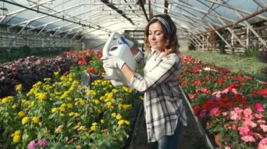 Kapalı alanda çiçek sulayan bir kadın.