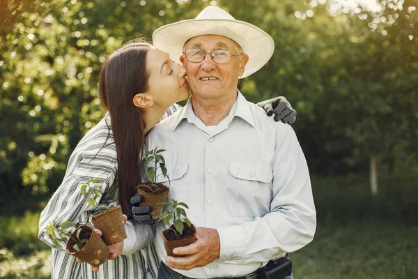 Portrait of senior man in a hat gardening with granddaugher — Stock Photo, Image