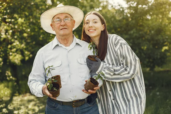 Портрет пожилого человека в шляпе садоводства с внучкой — стоковое фото