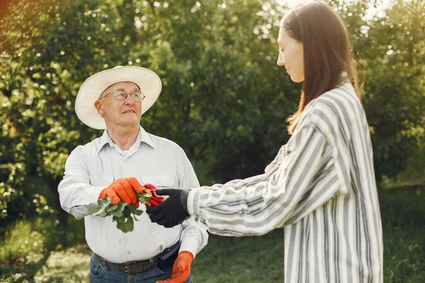 Portrait of senior man in a hat gardening with granddaugher — Stock Photo, Image