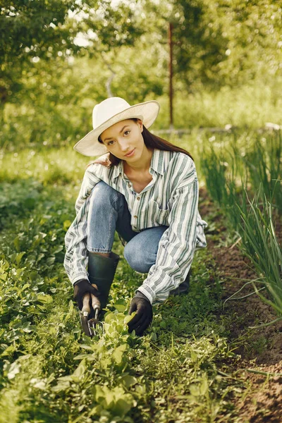 Kobieta w kapeluszu pracująca w ogrodzie — Zdjęcie stockowe