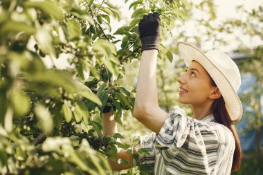 Bahçede çalışan şapkalı bir kadın.