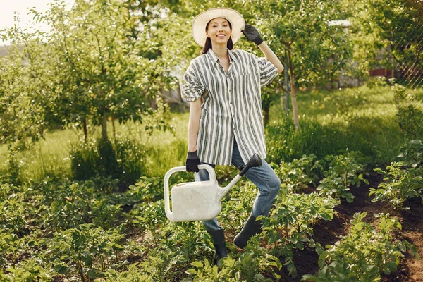 Kobieta w kapeluszu trzyma lejek i pracuje w ogrodzie — Zdjęcie stockowe
