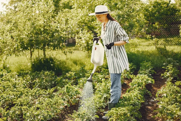 모자를 쓰고 깔때기를 들고 정원에서 일하는 여자 — 스톡 사진