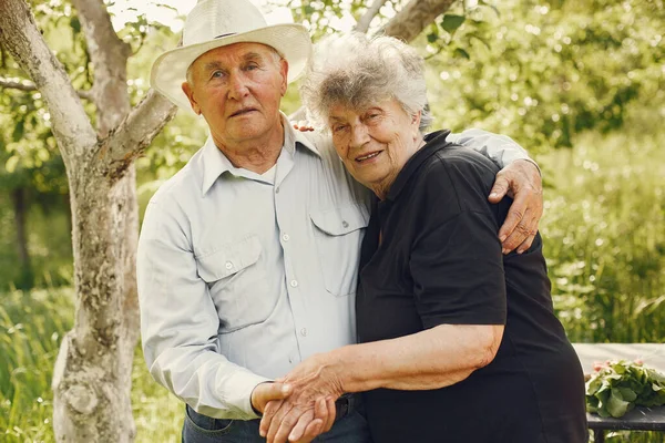 Beautiful old couple spend time in a summer garden — Stock Photo, Image