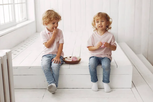 Lindos niños comiendo galletas en casa — Foto de Stock