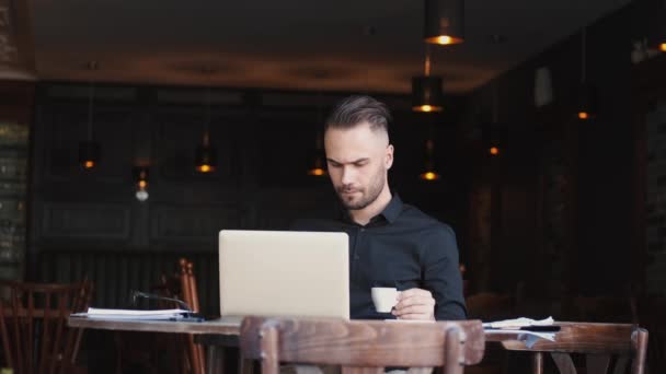 Bir kafede dizüstü bilgisayarla çalışan yakışıklı bir iş adamı. — Stok video