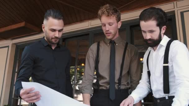 Ernsthafter Geschäftsmann arbeitet im Outdoor-Café mit einem großen Stück Papier — Stockvideo