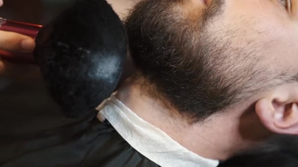 Парикмахер наносит лосьон на бороду человека 4k — стоковое видео