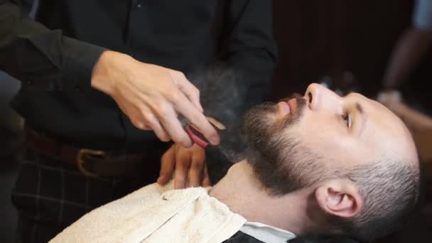 Barber applying lotion on mans beard 4k — Stock Video